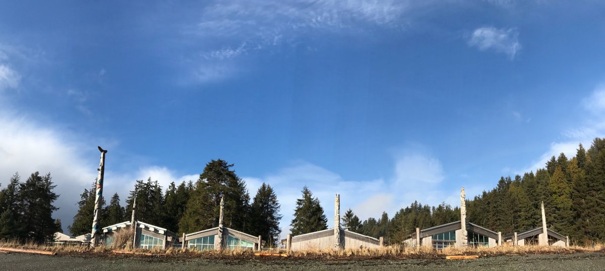 indigenous building with totem poles against blue sky