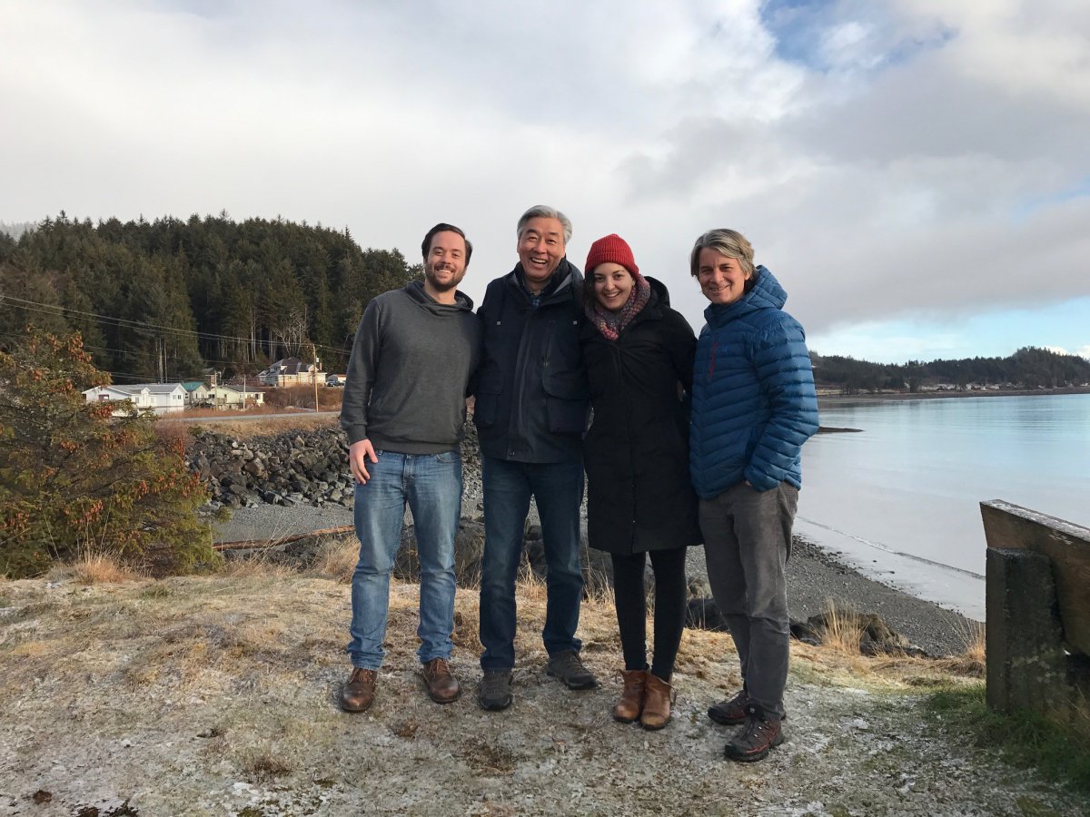 four people standing on a beach in the wintertime