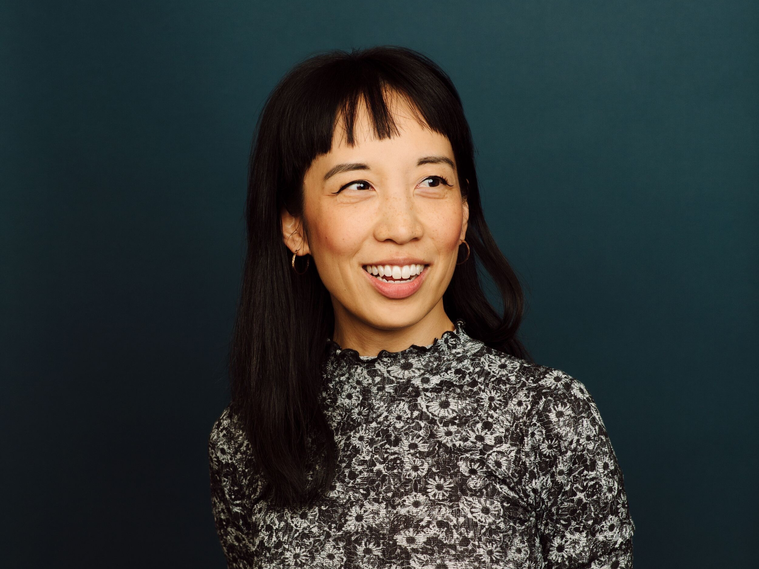 Megan Lau. Woman with black hair and bangs looking slightly to her left and smiling.